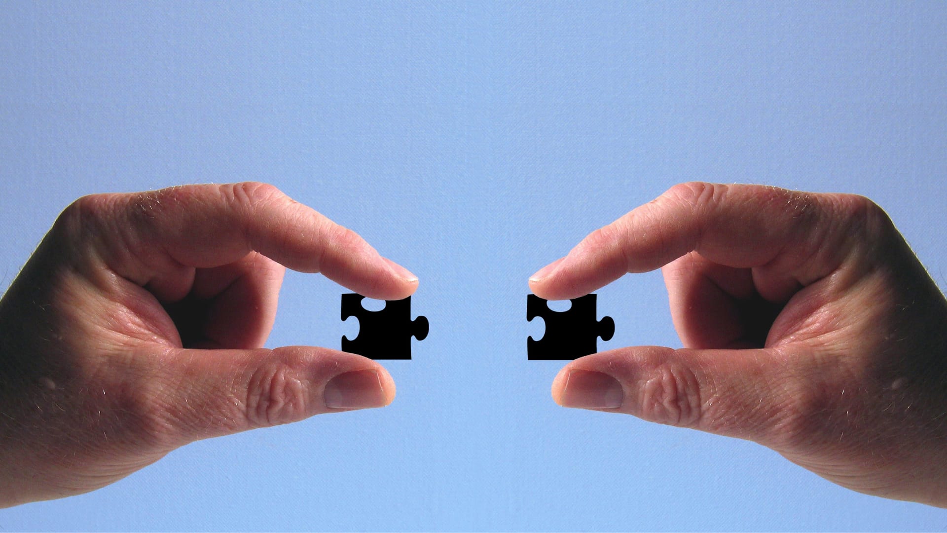 Duas mãos segurando peças iguais de quebra-cabeça